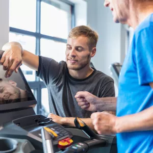 A Trainer Sets Up a Treadmill for a Patient