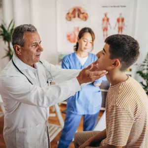 A Doctor Examines a Teenage Patients Face While a Nurse Takes Notes