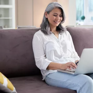 A woman using her computer while sitting on the couch.