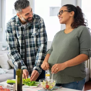 A pregnant woman and her husband make a healthy meal.
