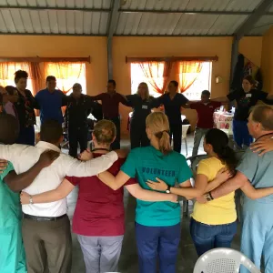 A group of physicians, nurses, and others in a group circle