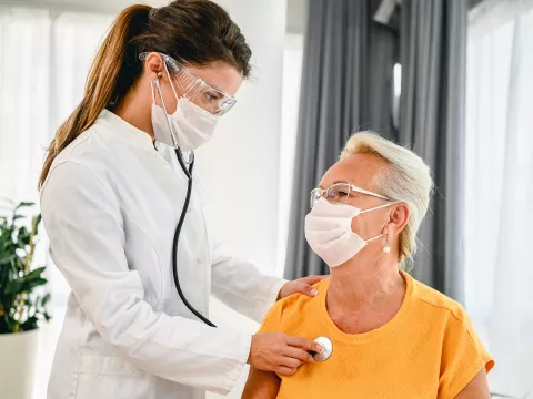 A doctor listens to a patient's breathing with a stethoscope