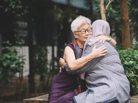 Two Women Embrace Outside in a Beautiful Nature Setting.