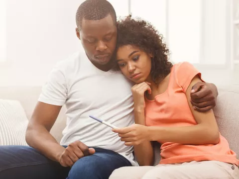 A Couple Embraces While Waiting for the Results of a Home Pregnancy Test.