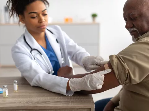 A Physician Puts a Bandage on an Injection Site After a Vaccine