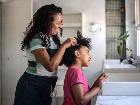 A Mother Helps Her Daughter with Her Hair in The Bathroom.
