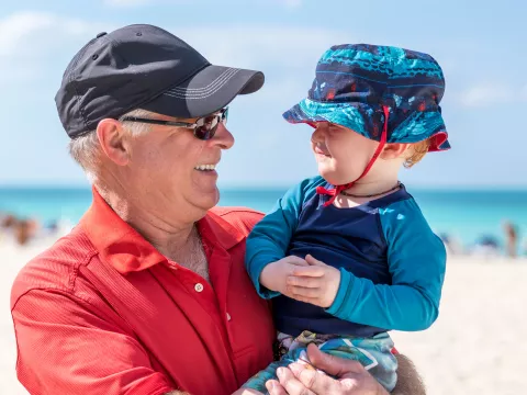 A Grandfather Holds His Grandson on the Beach