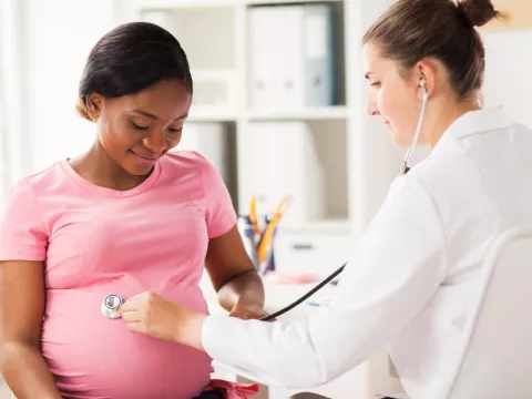 Doctor listening to pregnant woman's child in womb.
