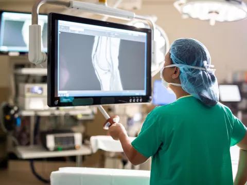 doctor in scrubs examining an x-ray in a surgical room