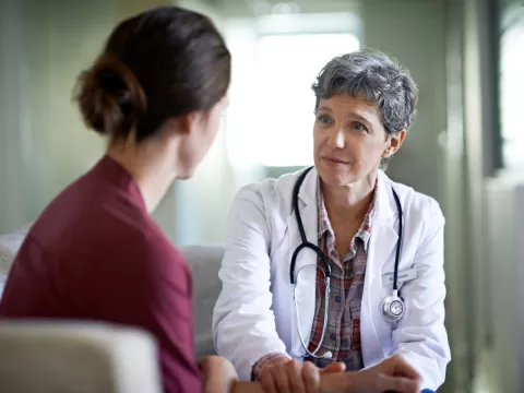 A female doctor comforts a young woman in her office