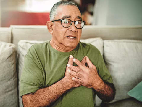 An older man holding his chest.