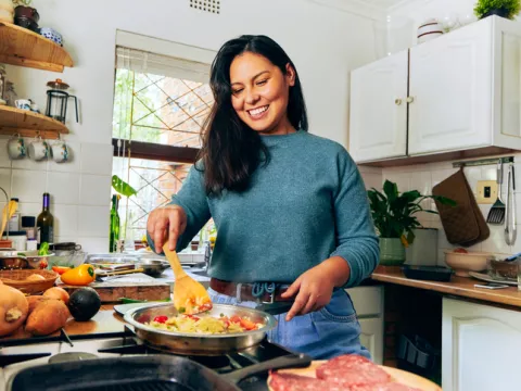 Woman cooking in kitchen smiling.