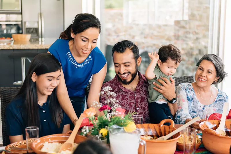 A Hispanic Family Sits Down to a Meal in Their Home.