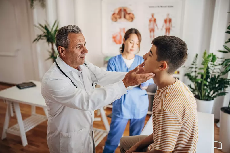 A Doctor Examines a Teenage Patients Face While a Nurse Takes Notes