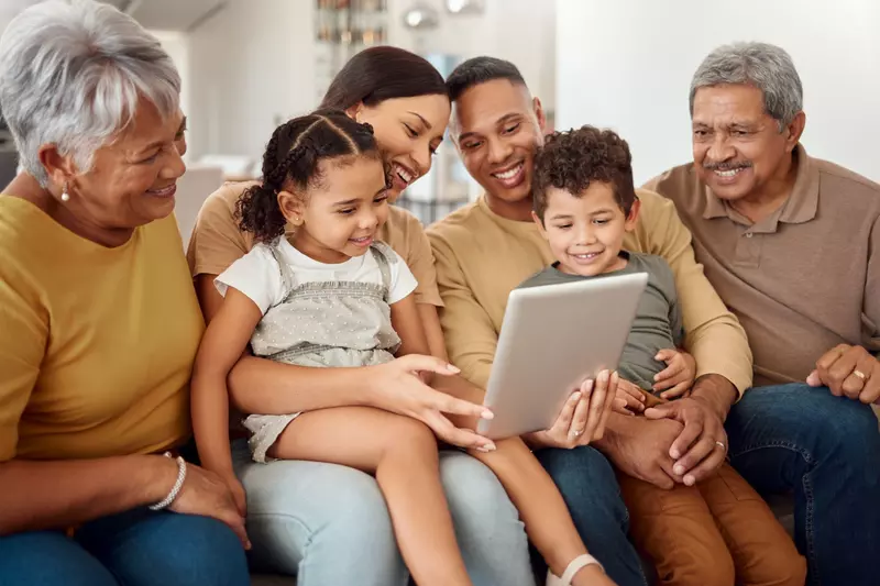 Hispanic Latino family on couch looking at iPad together.