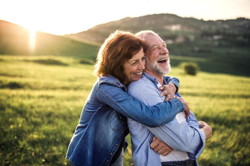 A Couple Hugs Out in a Field While Laughing