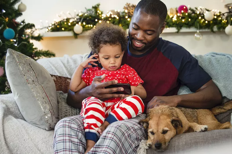 A father an son sit together on the couch during the holiday season. 