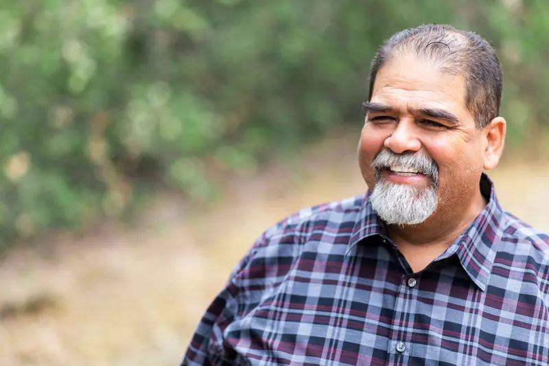 A mature man smiling and outdoors