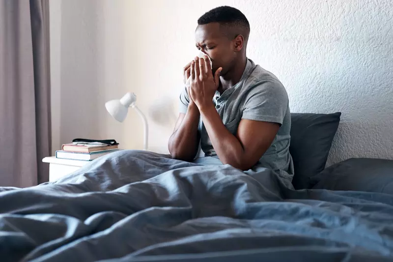 Man sneezing in bed.