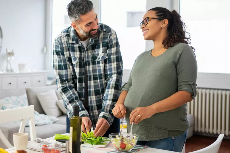 A pregnant woman and her husband make a healthy meal.