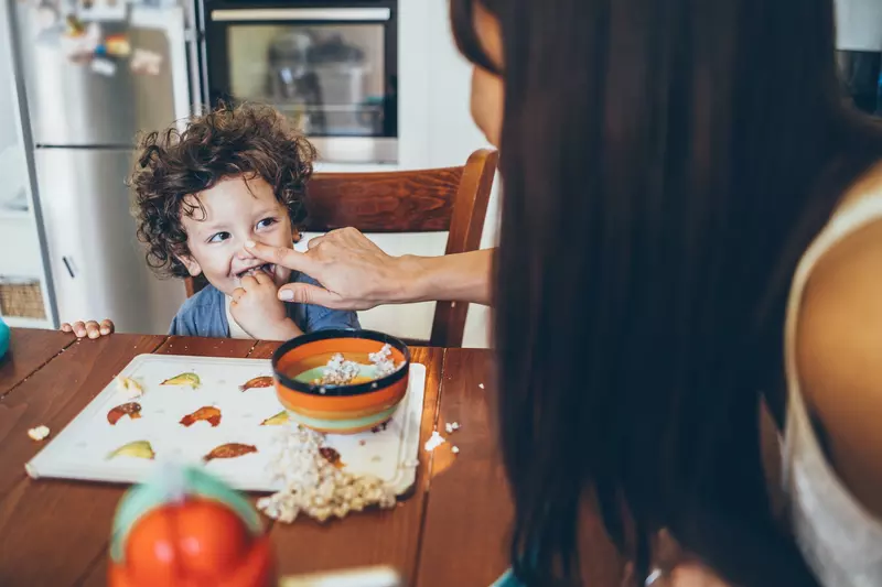 A young boy messily eats his breakfast