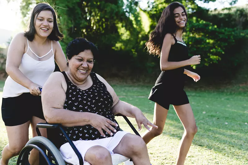 Woman in wheelchair with daughters outside 