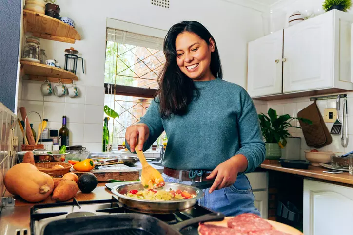 Woman cooking in kitchen smiling.