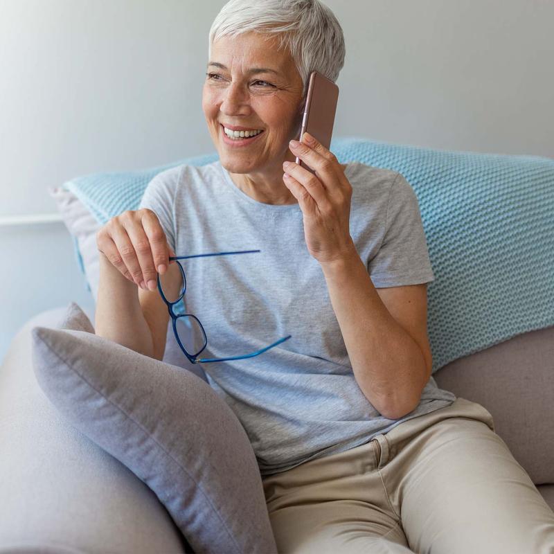 A woman on her cell phone at home on her couch.