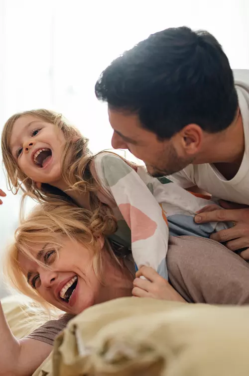 Family Laughing Together While Laying on a Bed