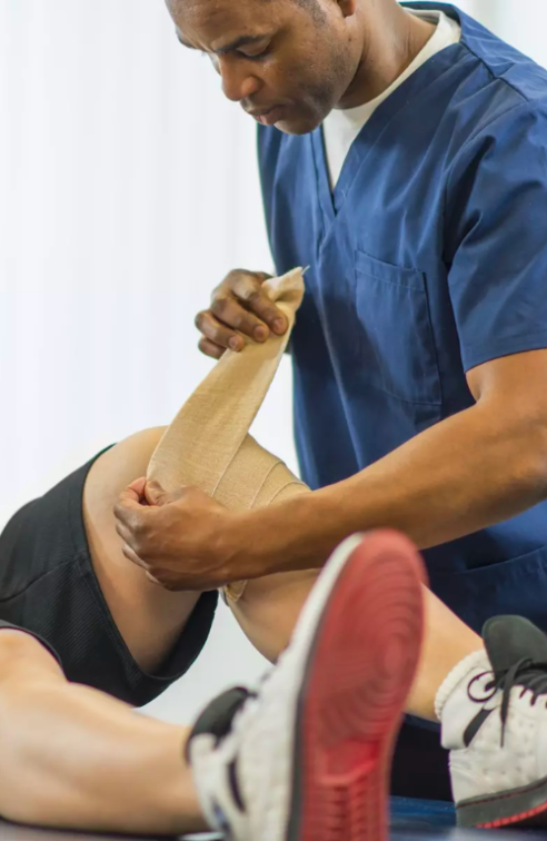 Physical Therapist Bandaging Patient's Knee