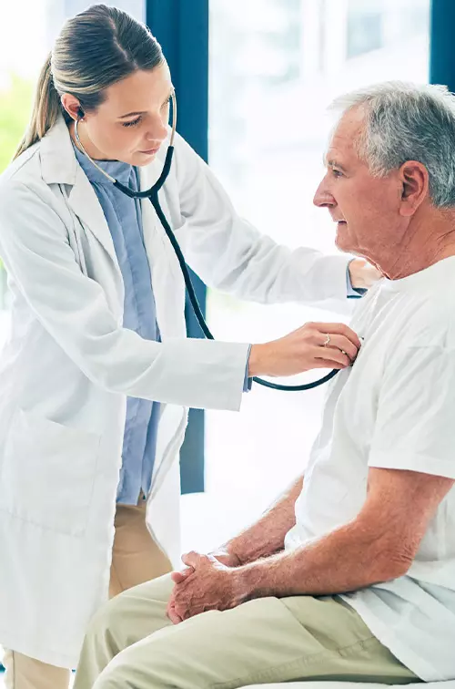 A female physician examining an older man's breathing with a stethoscope. 